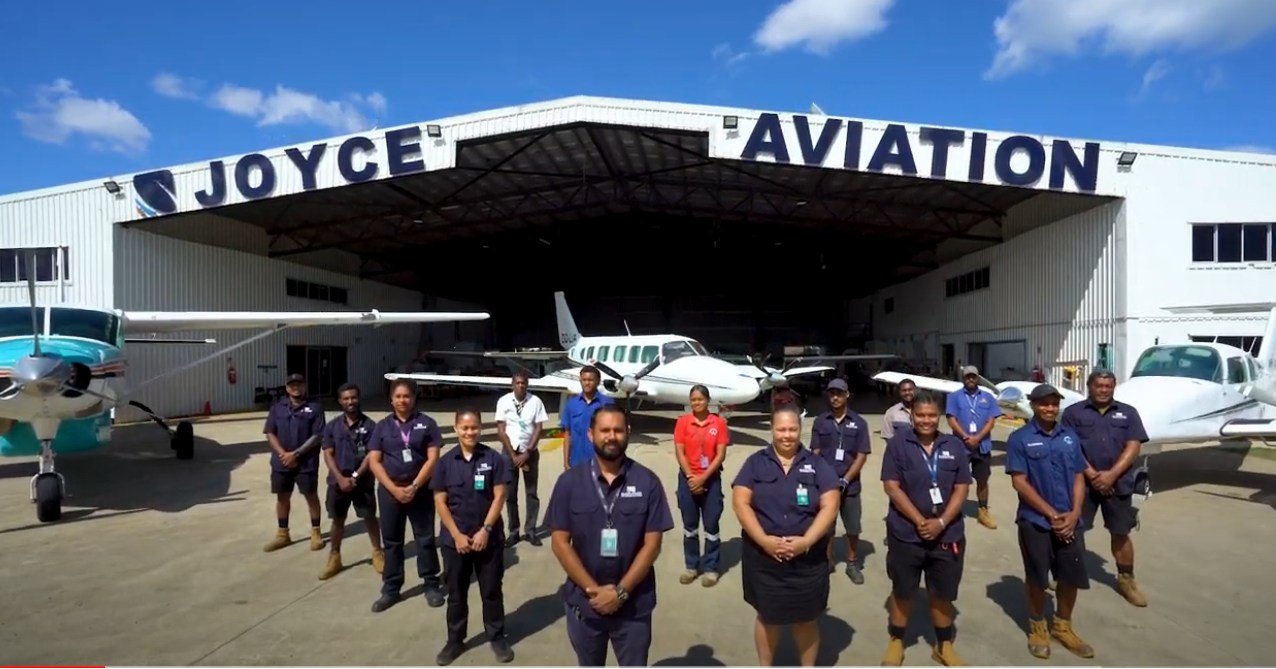 Joyce Aviation ground crew in navy uniforms at hangar